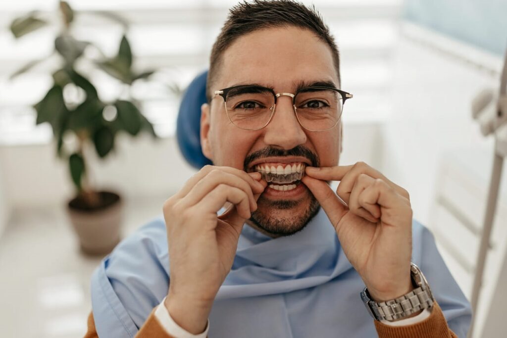 A man smiling as he puts in his clear retainer from a North Las Vegas orthodontist. 