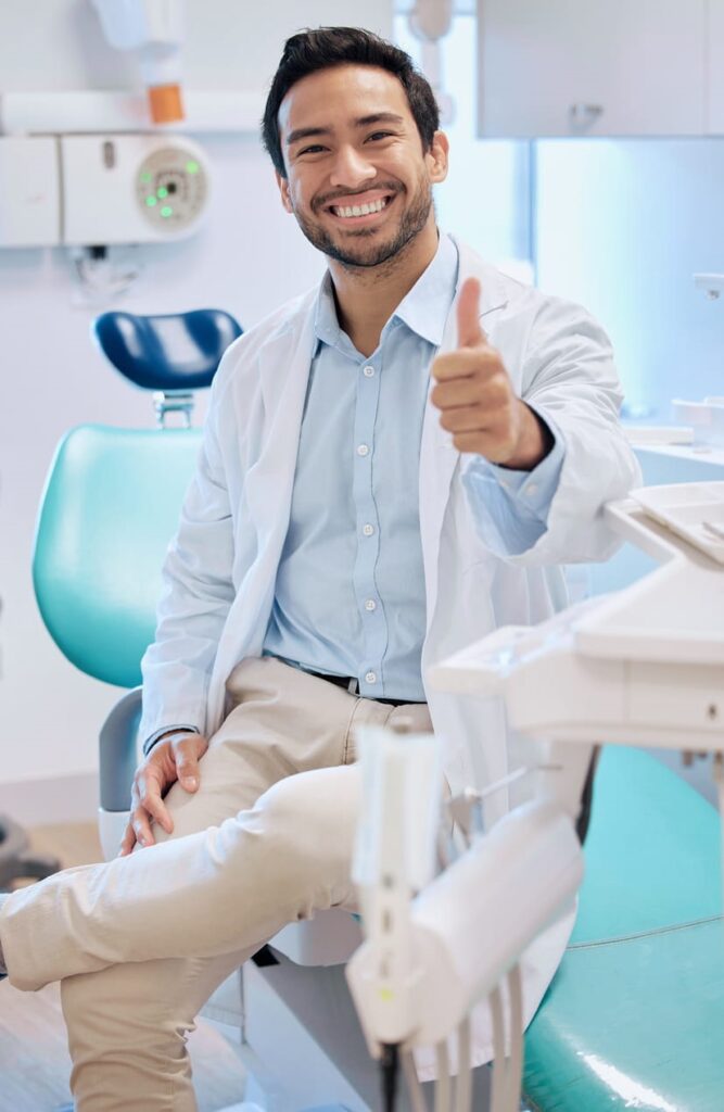 An oral surgeon smiling and giving a thumbs up.