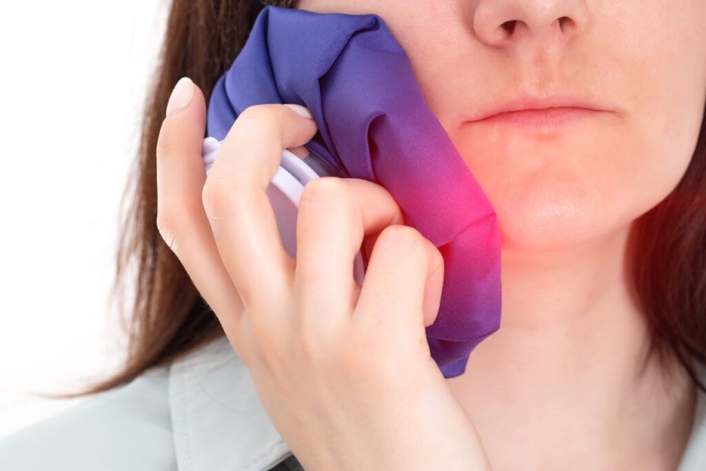 A person holding an ice bag against their jaw to help with pain.