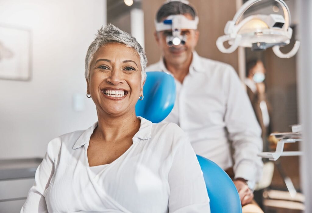 A woman smiling while at the dentists in Sparks, NV. The dentist is smiling behind her.