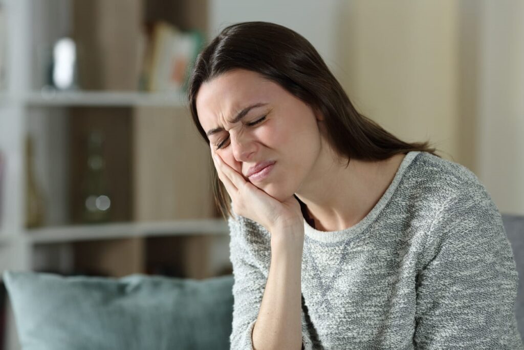 A woman holding her jaw in pain from a tooth abscess. 