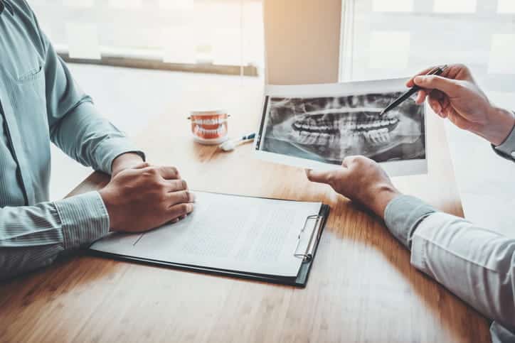 A dentist reviewing an X-ray with their patient after a dental emergency. 