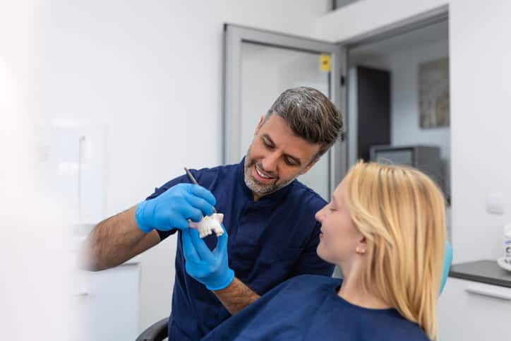 A dentist showing his patient how a dental bridge would work.