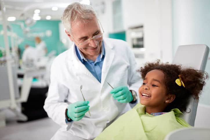 A pediatric dentist smiling with his pediatric patient.
