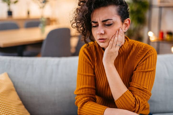 A woman holding her jaw in pain from a toothache.
