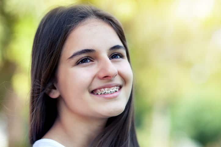 A girl smiling with metal braces.