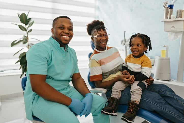 A pediatric dentist smiling with a woman and her son. 