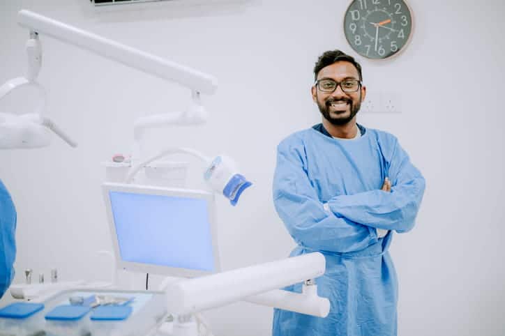 An oral surgeon smiling next to his dental equipment. 