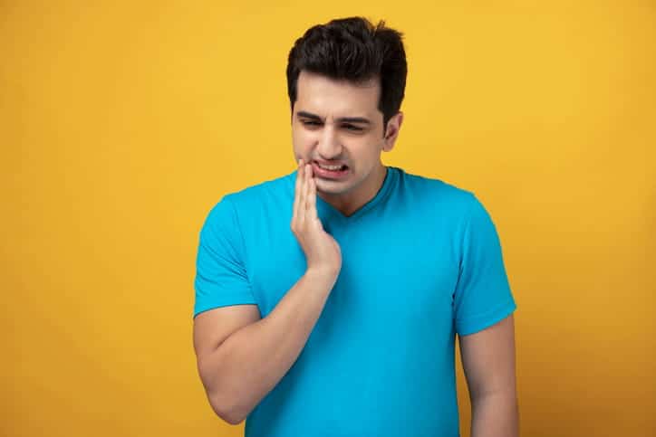 A man holding his face in pain after experiencing a chipped tooth.