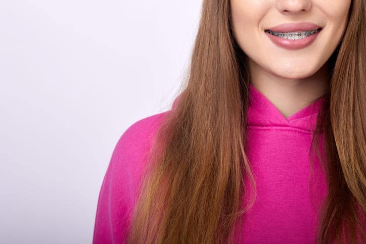 Focus is on a girl smiling while she shows off her metal braces.
