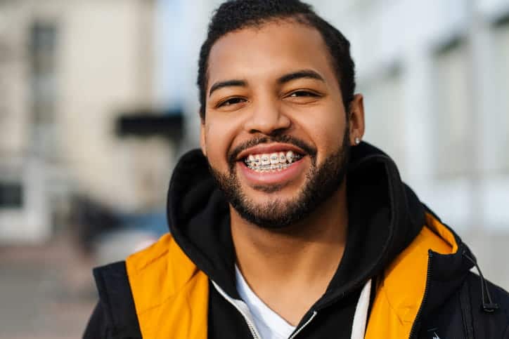 A man smiling with metal braces.