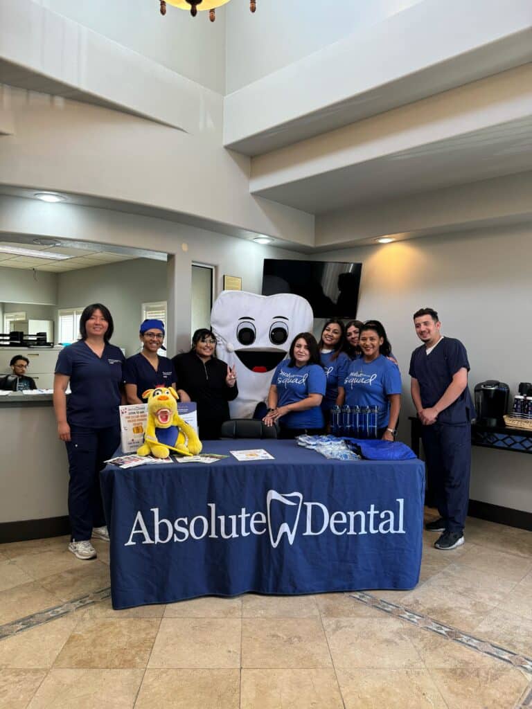 Group of absolute dental employees at table for adult dental day.