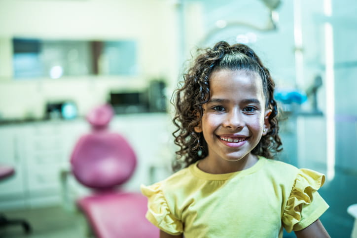 A young girl smiling at a dentist's office after a fluoride treatment.
