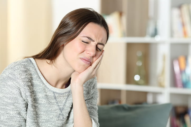 A woman holding her face in pain due to a dental abscess.