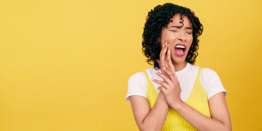 A woman holding her face in pain due to a tooth infection.