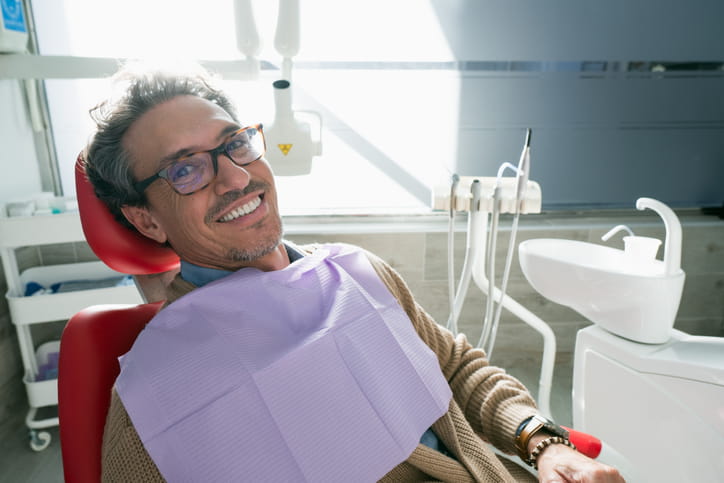A man smiling while sitting in a dental chair.