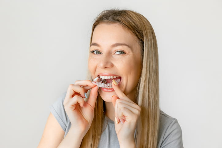 A woman putting in her Invisalign aligner.