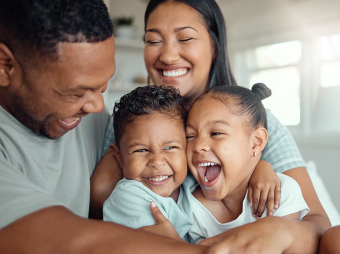 A family of four smiling together.