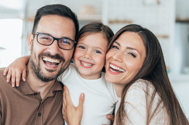 A family of three smiling together.