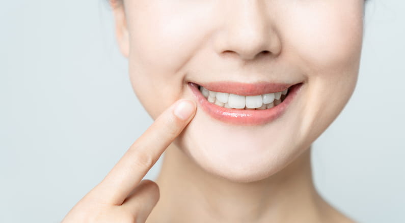 A woman pointing at her smile after a fluoride treatment.