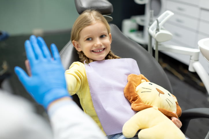 A young girl smiling and high fiving her dentist.