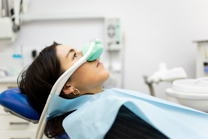 A woman with a mask over her nose at the dentist for sedation dentistry. 