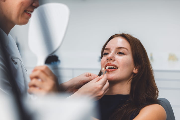 A dentist showing a patient different shades before doing a teeth whitening treatment.