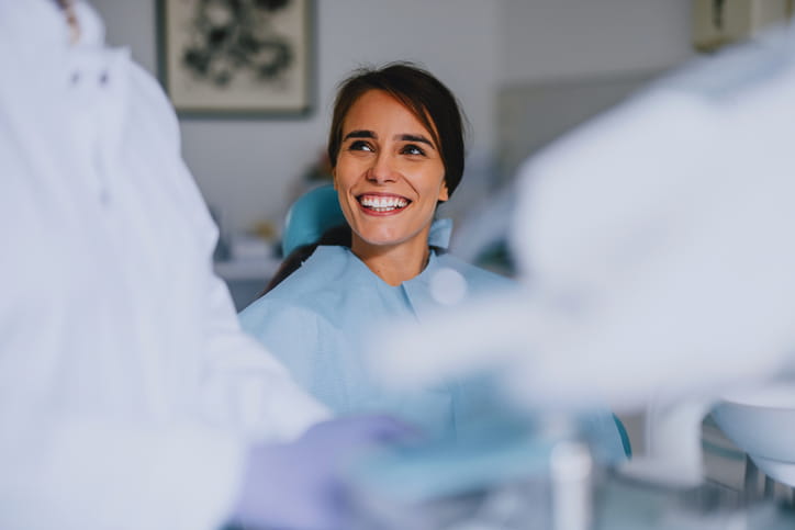 A woman smiling while she sits in a dental chair. 