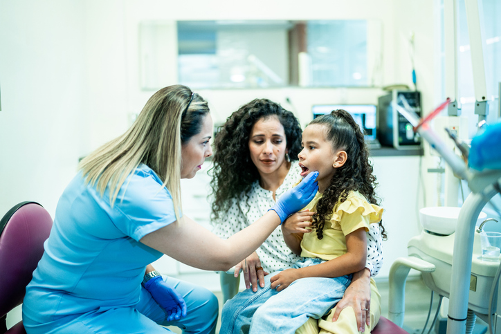 Dentist talking to mother and daughter patients in her office