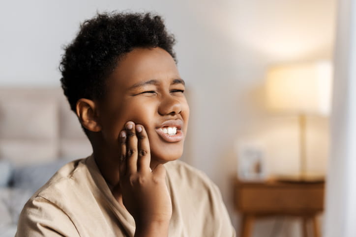 A kid holding his face in pain due to a toothache.