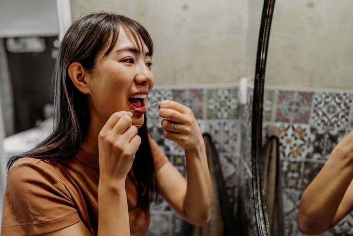 A woman flossing her teeth.