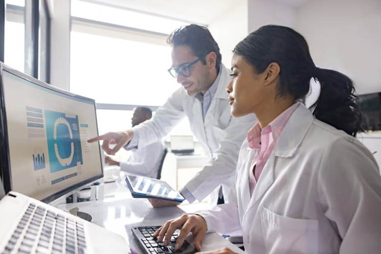 Two dentists work at a computer to discuss a patient's results.